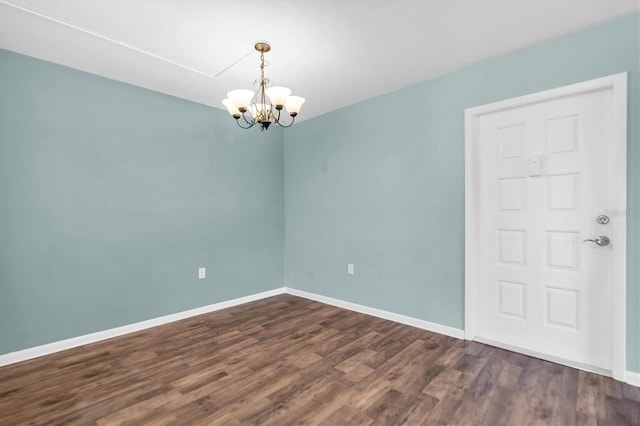 spare room with dark wood-type flooring and a chandelier