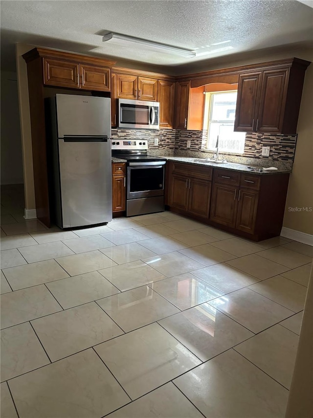 kitchen with light tile patterned flooring, sink, a textured ceiling, backsplash, and appliances with stainless steel finishes