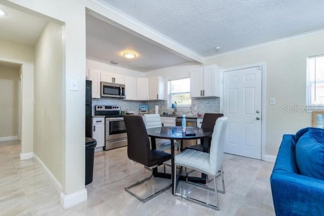 dining room with a textured ceiling, ornamental molding, and sink