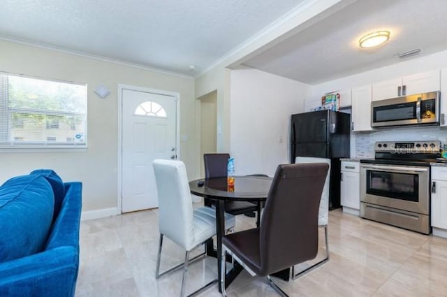 kitchen featuring white cabinets, appliances with stainless steel finishes, crown molding, and tasteful backsplash