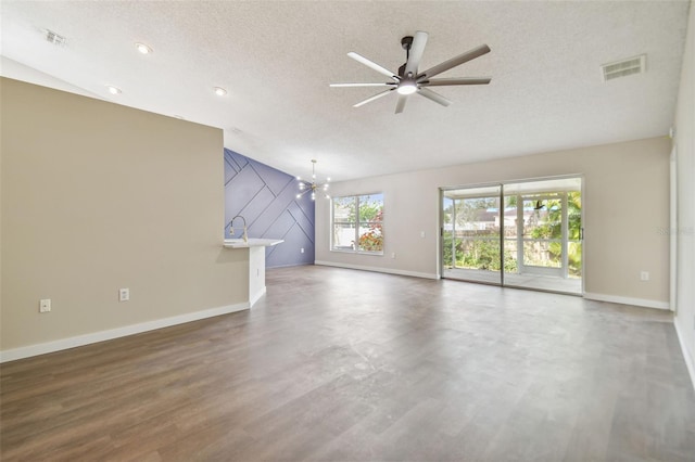 unfurnished living room with ceiling fan with notable chandelier, wood-type flooring, a textured ceiling, and vaulted ceiling