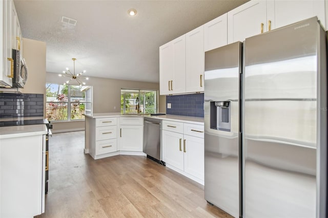 kitchen with kitchen peninsula, appliances with stainless steel finishes, tasteful backsplash, light hardwood / wood-style flooring, and white cabinets