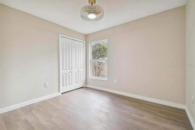 unfurnished bedroom featuring a closet, light hardwood / wood-style floors, and a textured ceiling