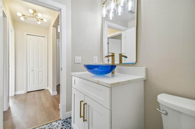 bathroom featuring vanity, toilet, an inviting chandelier, and hardwood / wood-style flooring