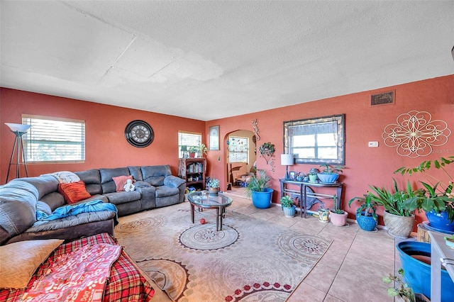 living room featuring a wealth of natural light, a textured ceiling, and light tile patterned flooring