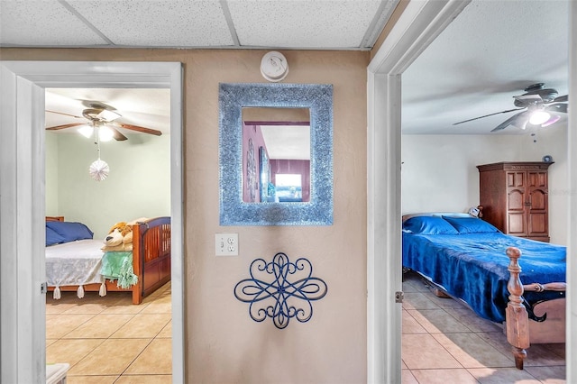 bedroom featuring ceiling fan, light tile patterned floors, and a paneled ceiling