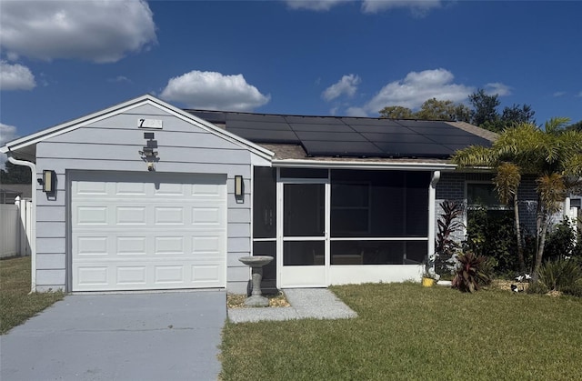 view of front of property with a sunroom, a front yard, solar panels, and a garage