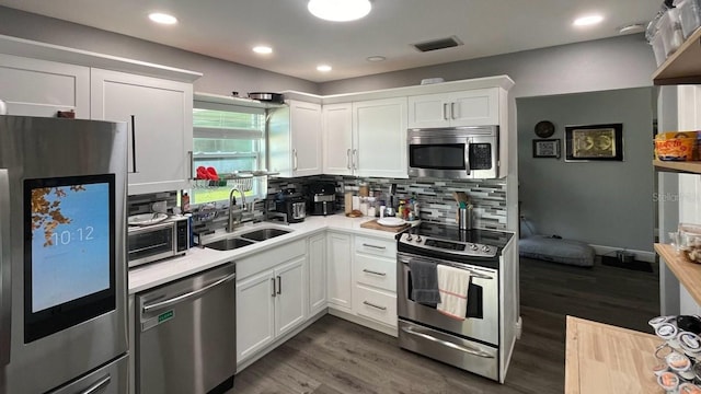 kitchen with white cabinets, backsplash, stainless steel appliances, dark hardwood / wood-style floors, and sink