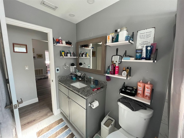 bathroom with hardwood / wood-style flooring, vanity, and toilet