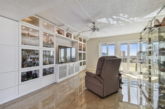 sitting room with ceiling fan and a textured ceiling