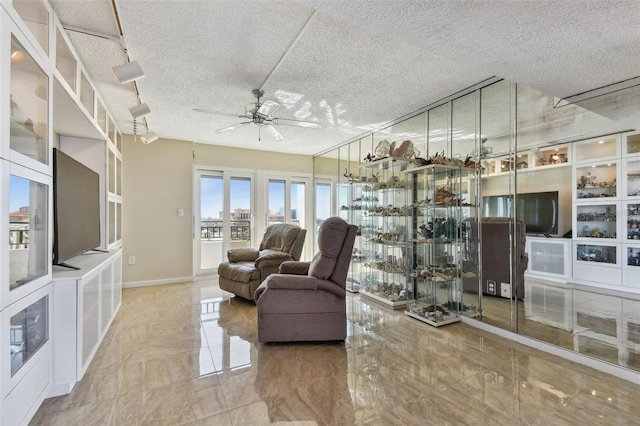 living room featuring ceiling fan and a textured ceiling