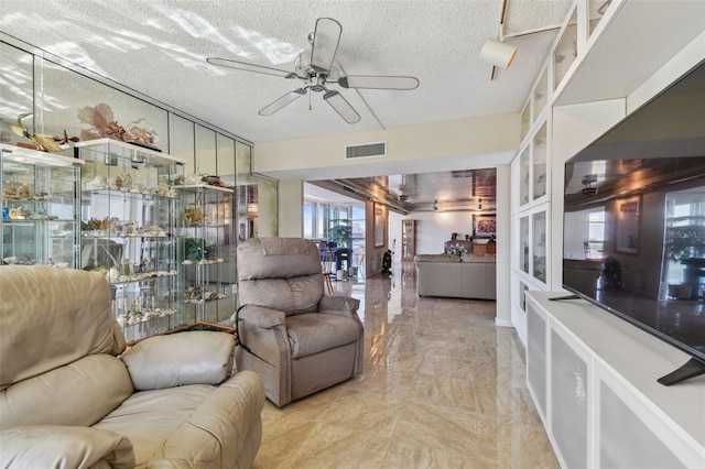 living room with ceiling fan and a textured ceiling