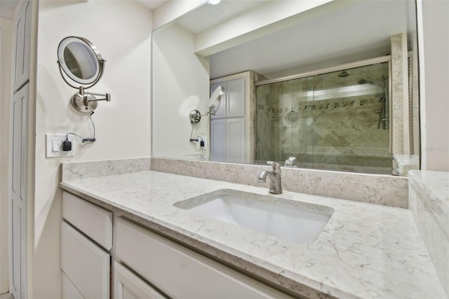 bathroom featuring a shower with door and vanity