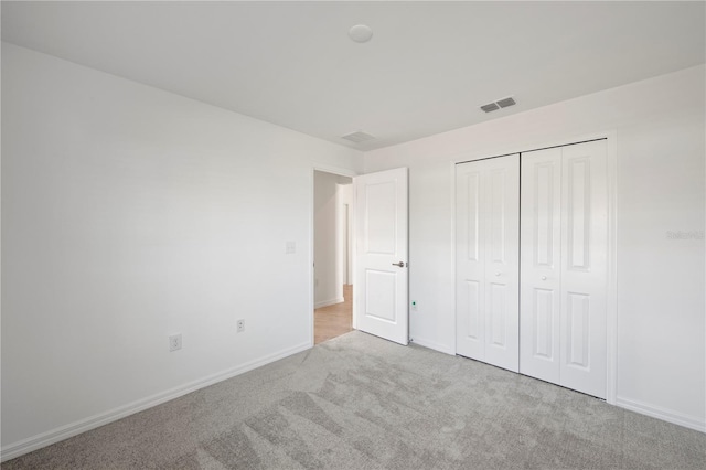 unfurnished bedroom with light carpet and a closet