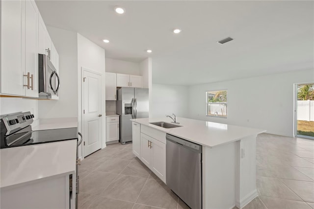 kitchen with stainless steel appliances, white cabinets, a wealth of natural light, and a center island with sink