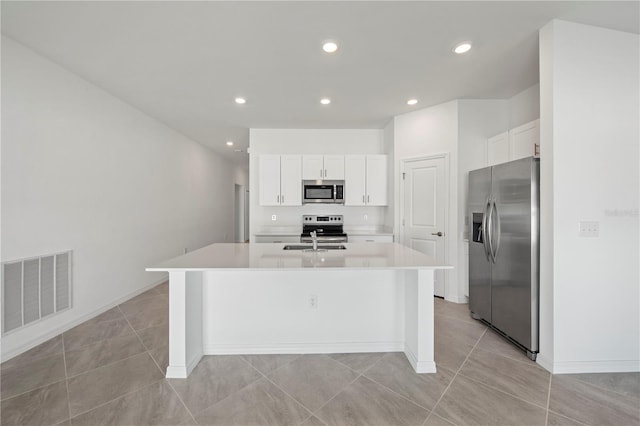 kitchen featuring an island with sink, white cabinetry, and stainless steel appliances