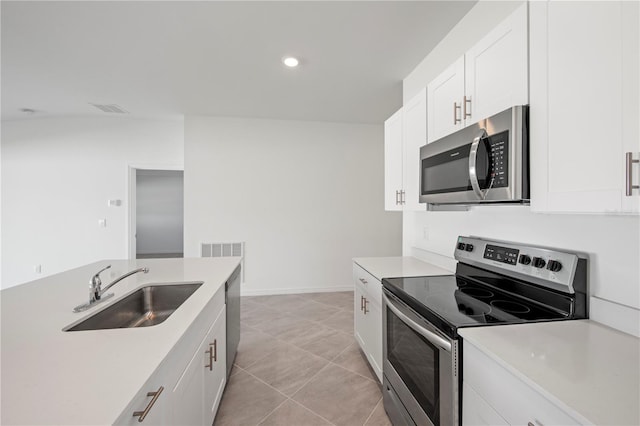 kitchen featuring stainless steel appliances, white cabinetry, light tile patterned floors, and sink