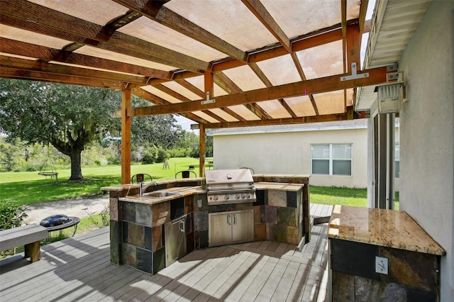 wooden deck featuring area for grilling, an outdoor kitchen, a lawn, a pergola, and sink