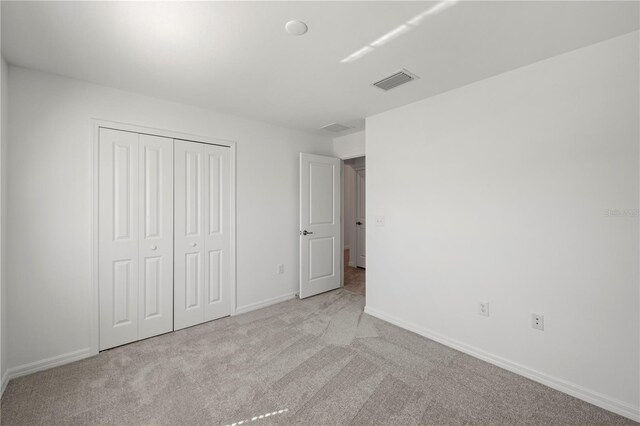 unfurnished bedroom with light carpet and a closet