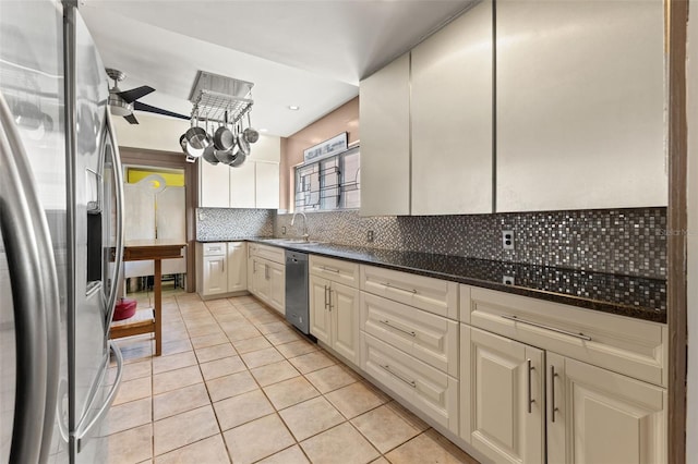 kitchen featuring light tile patterned flooring, sink, tasteful backsplash, cream cabinets, and stainless steel appliances