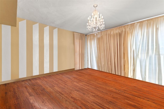 spare room with a chandelier and hardwood / wood-style flooring