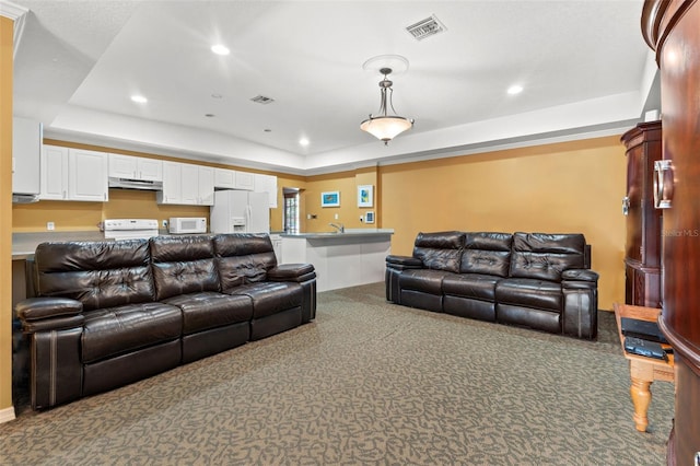 living room with a tray ceiling and carpet flooring