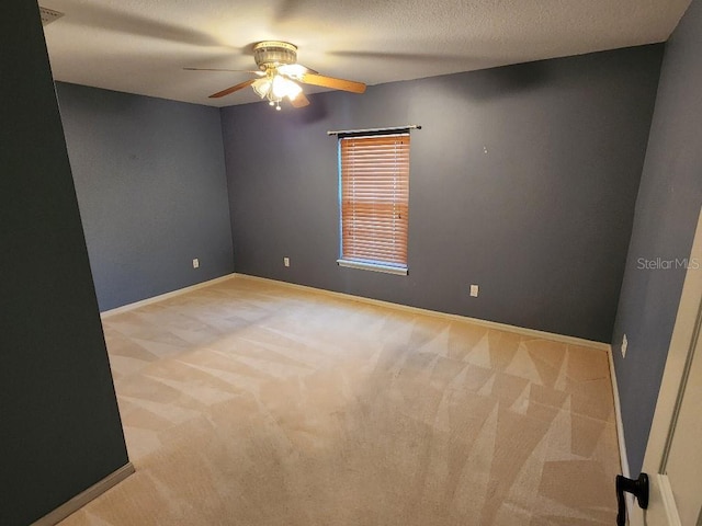 carpeted empty room with ceiling fan and a textured ceiling