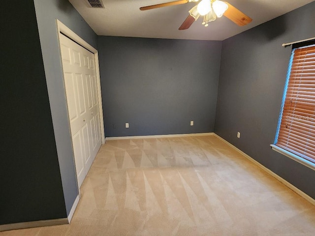 unfurnished bedroom featuring ceiling fan, a closet, and light colored carpet