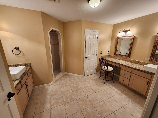 bathroom with a shower, vanity, and tile patterned floors