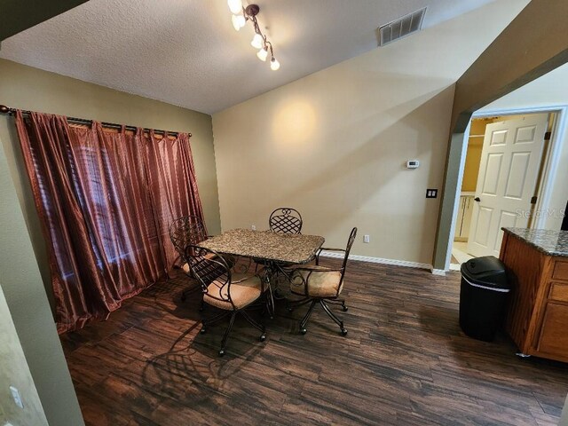 dining room featuring a textured ceiling, dark hardwood / wood-style flooring, and rail lighting