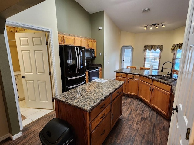 kitchen featuring a center island, black appliances, sink, dark stone countertops, and dark hardwood / wood-style flooring