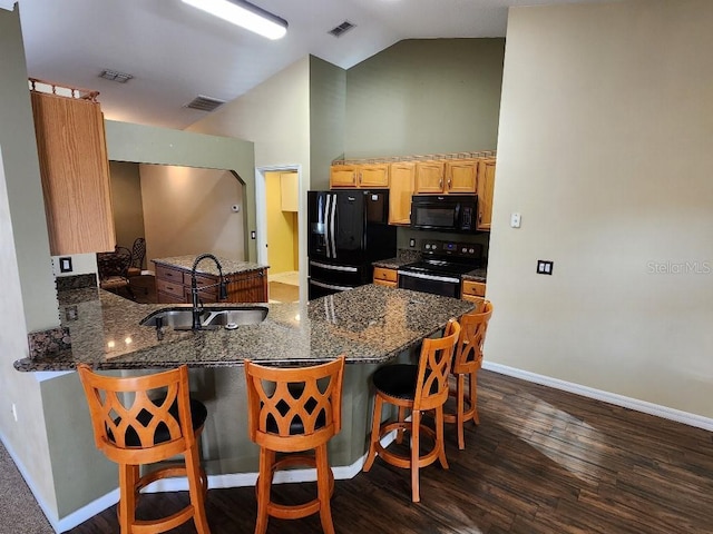 kitchen featuring sink, dark wood-type flooring, kitchen peninsula, vaulted ceiling, and black appliances