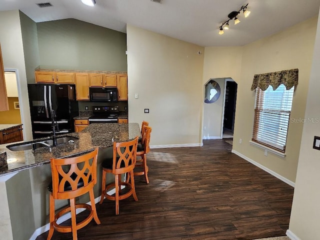 kitchen with a kitchen breakfast bar, dark wood-type flooring, sink, black appliances, and lofted ceiling