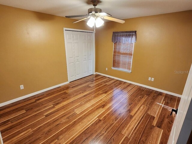 unfurnished bedroom featuring wood-type flooring, a closet, and ceiling fan