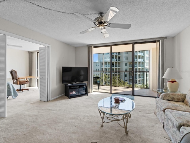 living area with carpet floors, expansive windows, a ceiling fan, and a textured ceiling