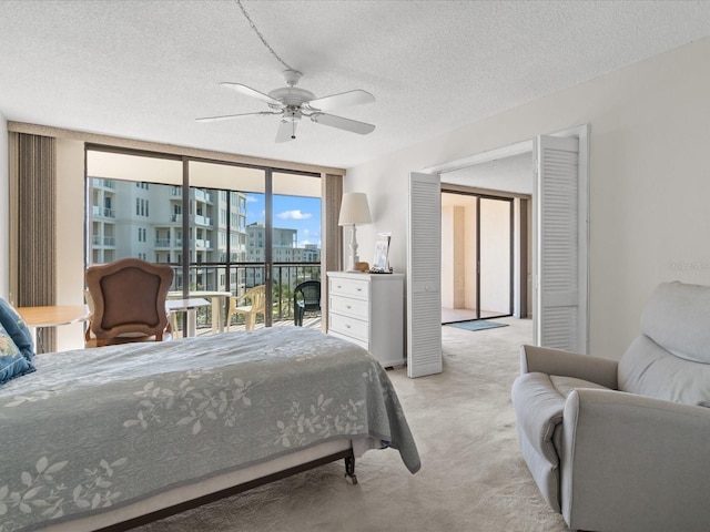 bedroom featuring floor to ceiling windows, a city view, light colored carpet, a textured ceiling, and access to outside