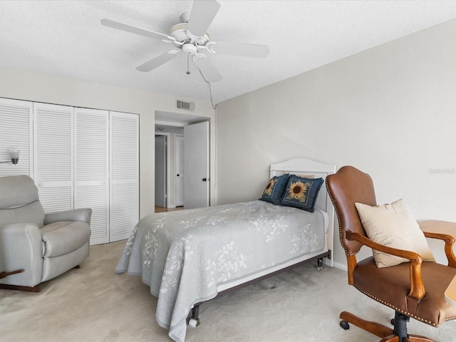 bedroom with visible vents, a ceiling fan, carpet, a textured ceiling, and a closet