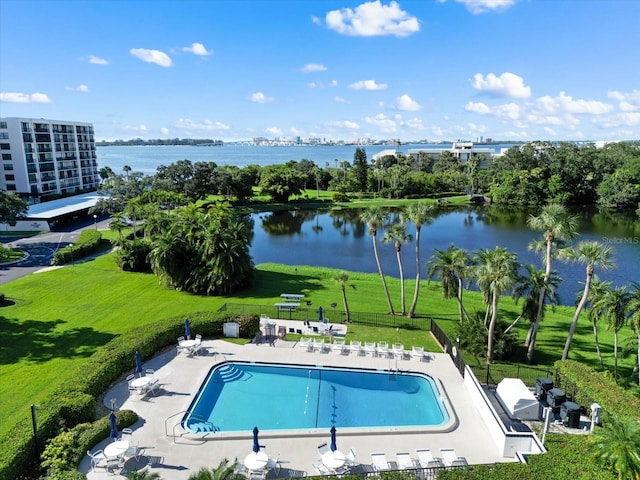 pool with a patio area, a water view, and fence