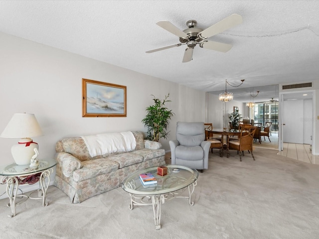 living area featuring light carpet, visible vents, a textured ceiling, and ceiling fan with notable chandelier