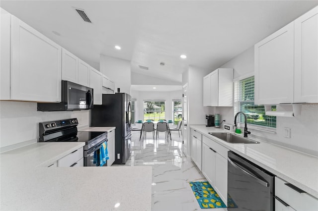 kitchen with lofted ceiling, appliances with stainless steel finishes, white cabinetry, and sink