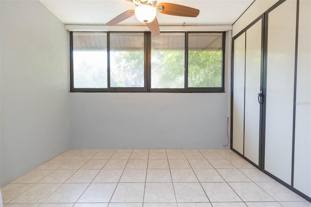 tiled spare room featuring ceiling fan