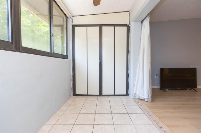 spare room featuring a textured ceiling, lofted ceiling, light tile patterned flooring, and ceiling fan