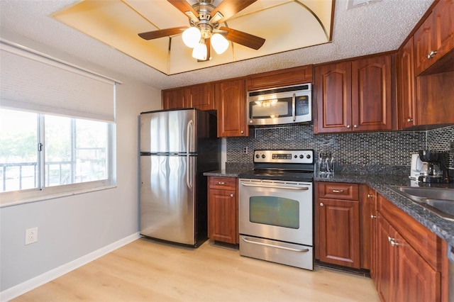 kitchen featuring appliances with stainless steel finishes, light hardwood / wood-style floors, backsplash, a textured ceiling, and ceiling fan