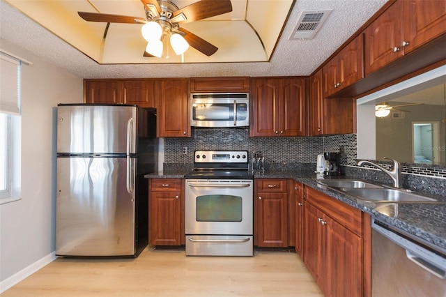 kitchen featuring a textured ceiling, stainless steel appliances, sink, and light hardwood / wood-style flooring