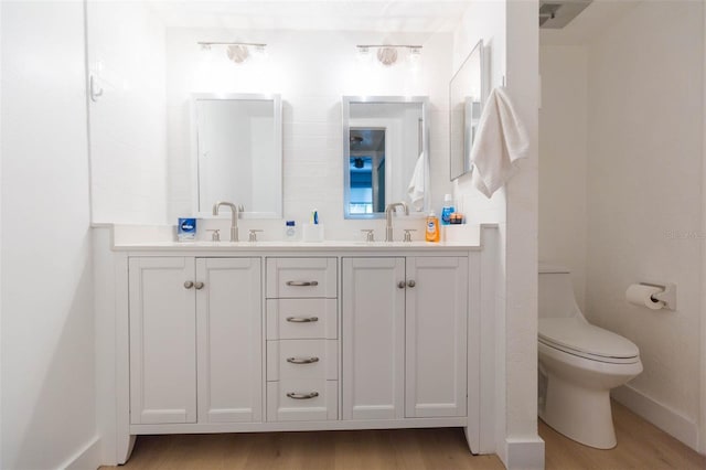 bathroom with wood-type flooring, vanity, and toilet