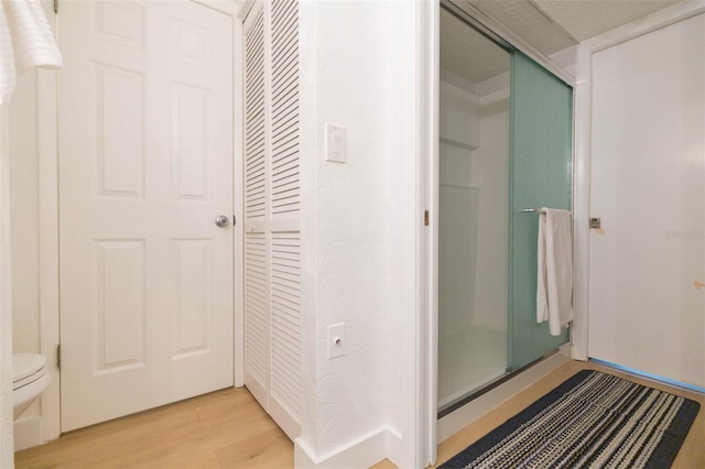 bathroom featuring a shower stall, toilet, and wood finished floors