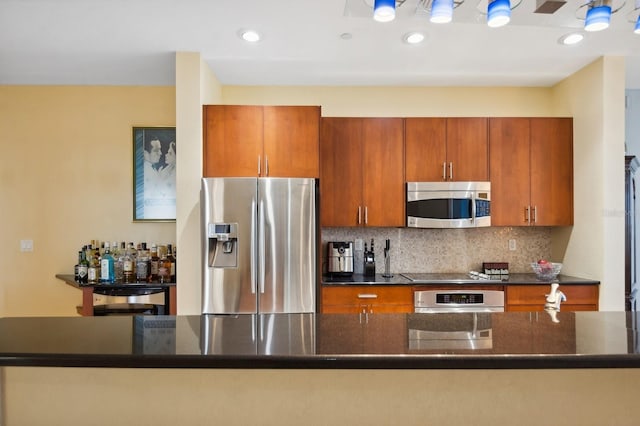 kitchen with dark stone countertops, appliances with stainless steel finishes, and tasteful backsplash