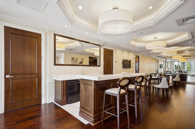 bar featuring a raised ceiling, crown molding, decorative light fixtures, and dark hardwood / wood-style flooring