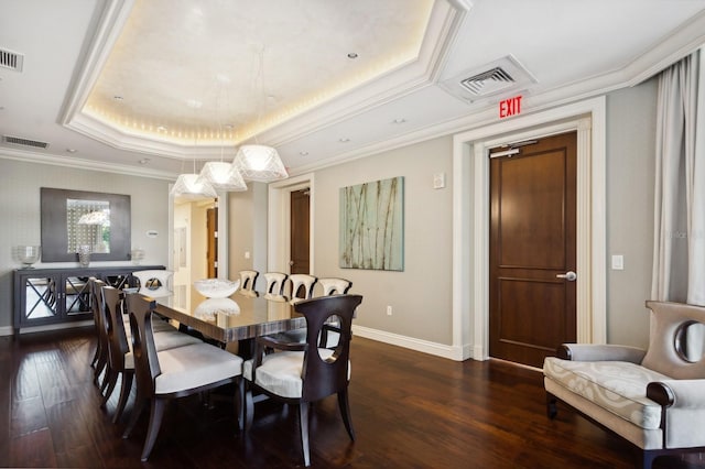 dining space with crown molding, a tray ceiling, dark wood-type flooring, and a chandelier