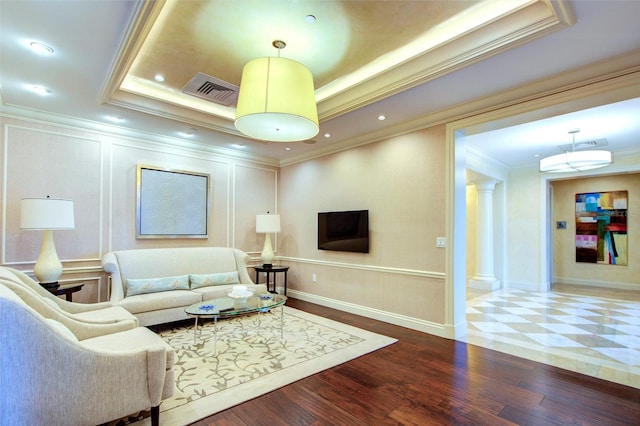 living room with wood-type flooring, a tray ceiling, ornamental molding, and ornate columns